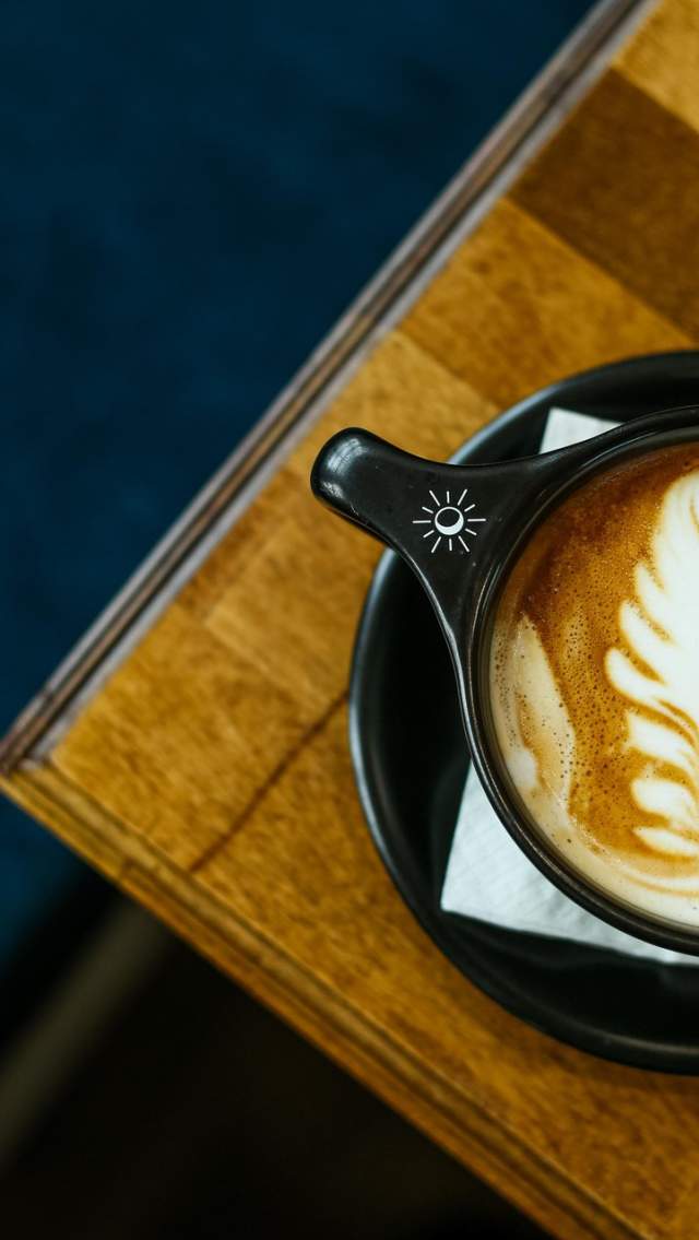 Overhead view of a latte with leaf-shaped foam art in a black cup at Tandem Coffee & Cocktails in Mandeville.
Caption: Latte art takes center stage at Tandem Coffee & Cocktails in Mandeville.