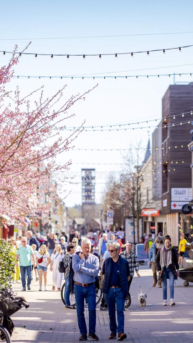 Mennesker som går i gågata og sitter på uteserveringen i Sarpsborg sentrum. Foto.
