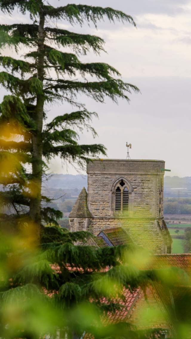 A church in the Lincolnshire Wolds with blurred trees in the foreground.