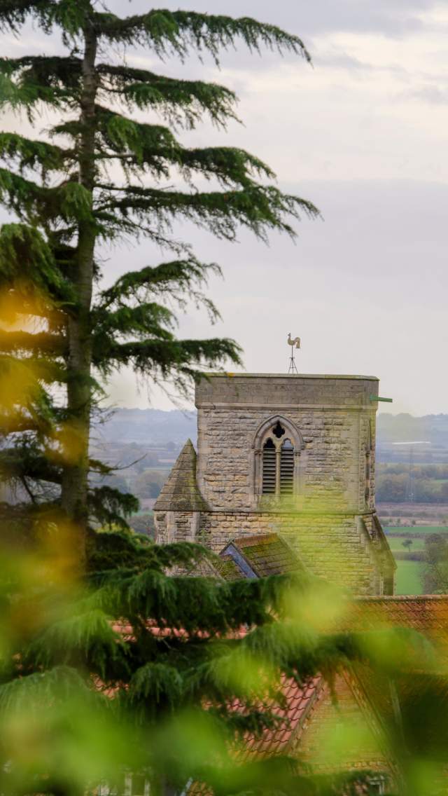 A church in the Lincolnshire Wolds with blurred trees in the foreground.