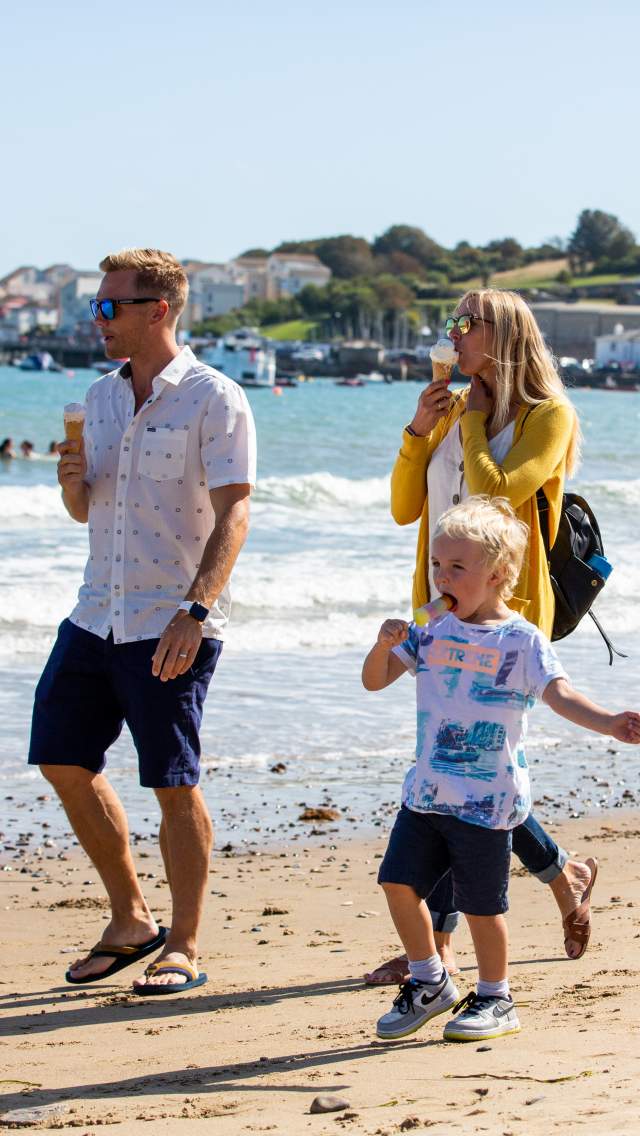 Family enjoying ice creams walking along Swanage Beach