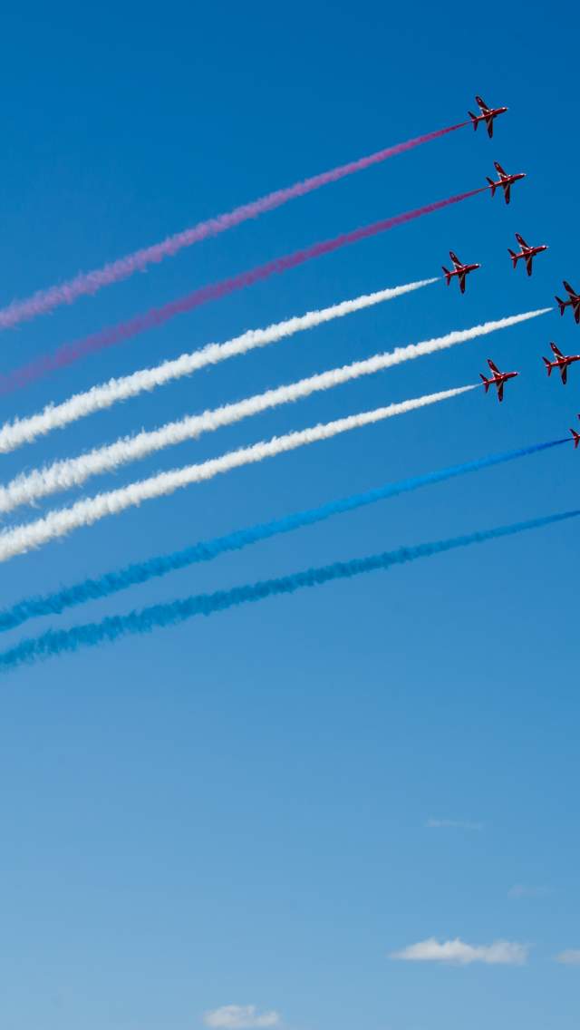 Red arrows flying in formation with coloured trails