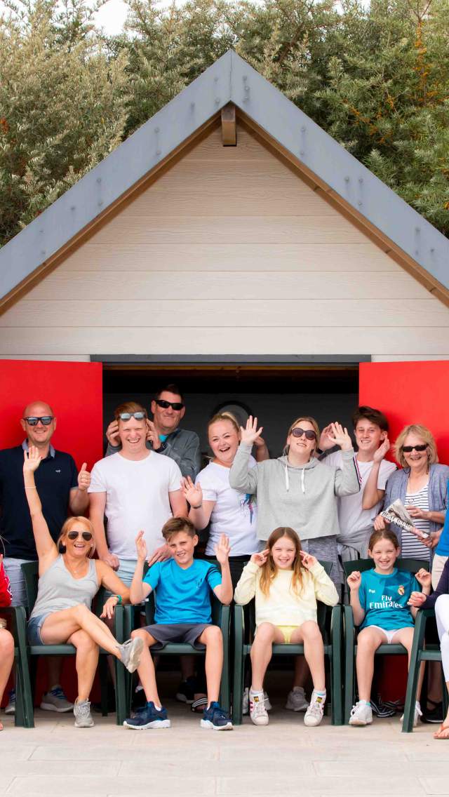 Family sitting outside a beach hut on Swanage seafront in Dorset