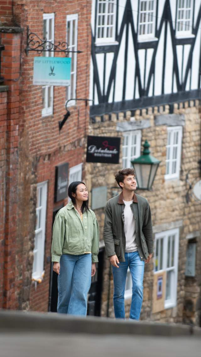 A couple walking up Steep Hill in Lincoln, with historic architecture lining the street
