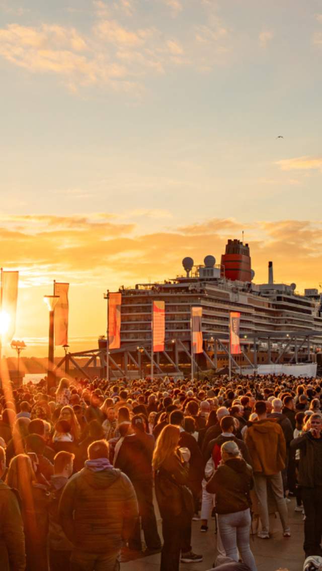 Liverpool Pier Head, busy with visitors and the sun going down across the River creating a golden light