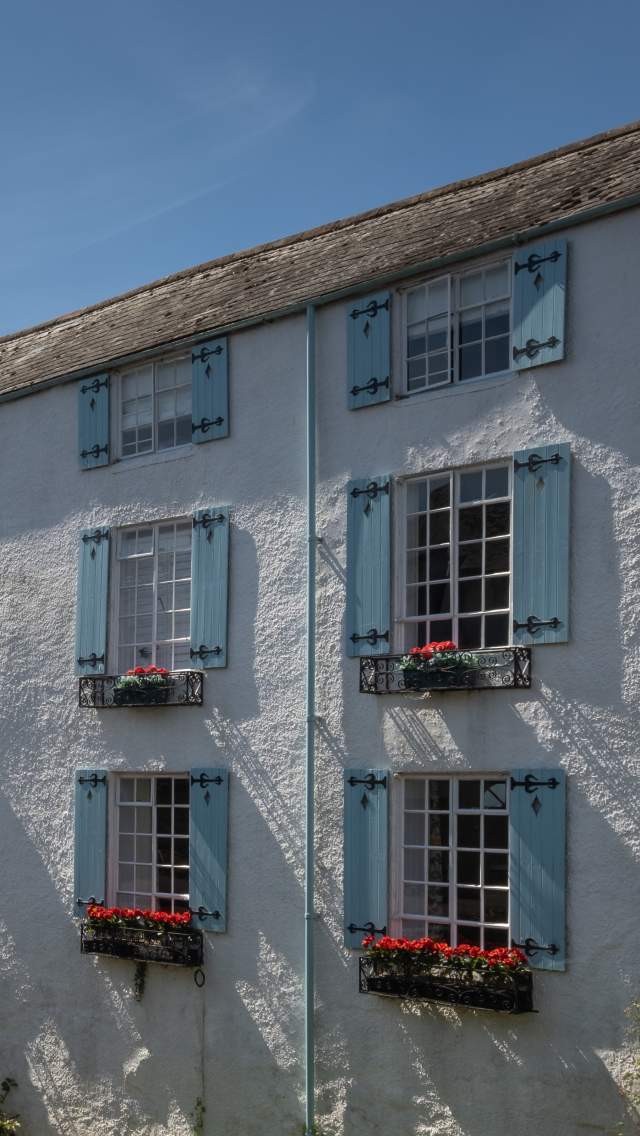 A white house with blue shutters on the windows next to the River Lym at Lyme Regis in Dorset