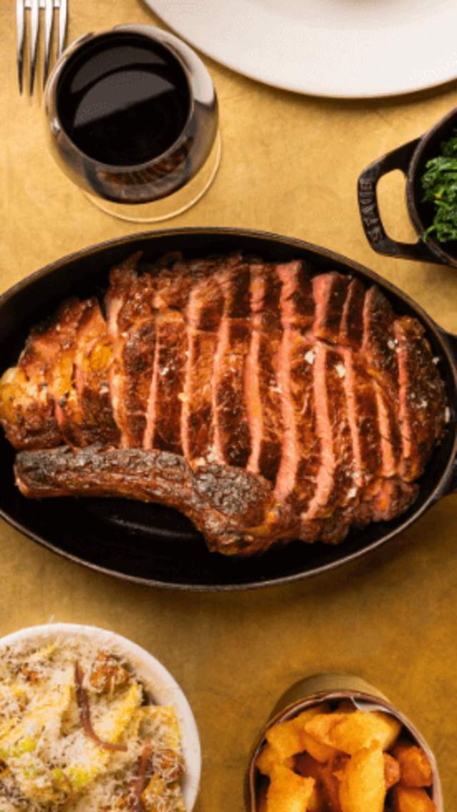 A bird's eye view of food on a table including steak, spinach and chips.