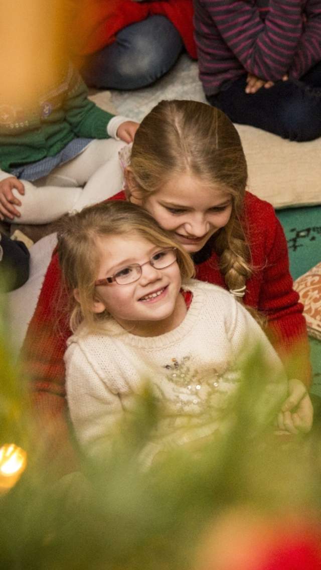 Children sitting on the floor listening to stories being told by Father Christmas