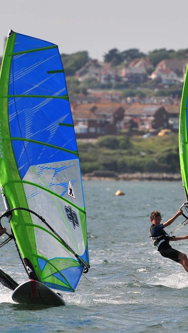 Three boys windsurfing with the Official Test Centre in Portland Harbour, Dorset