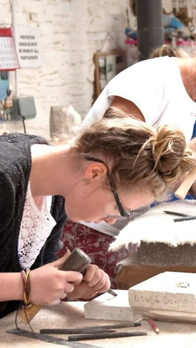 A group of people carving stone at Burngate Stone Carving Centre