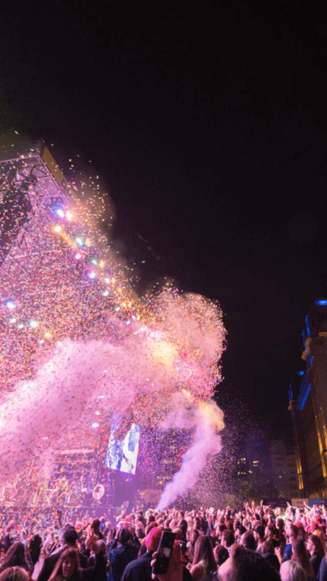 Crowds in front of the stage by the Royal Liver Building. Dry ice and confetti canons are spraying into the air and the sky is dark.