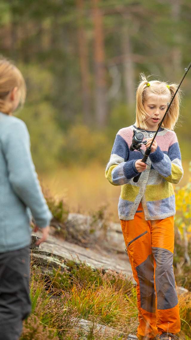 To jenter som fisker ved et vann