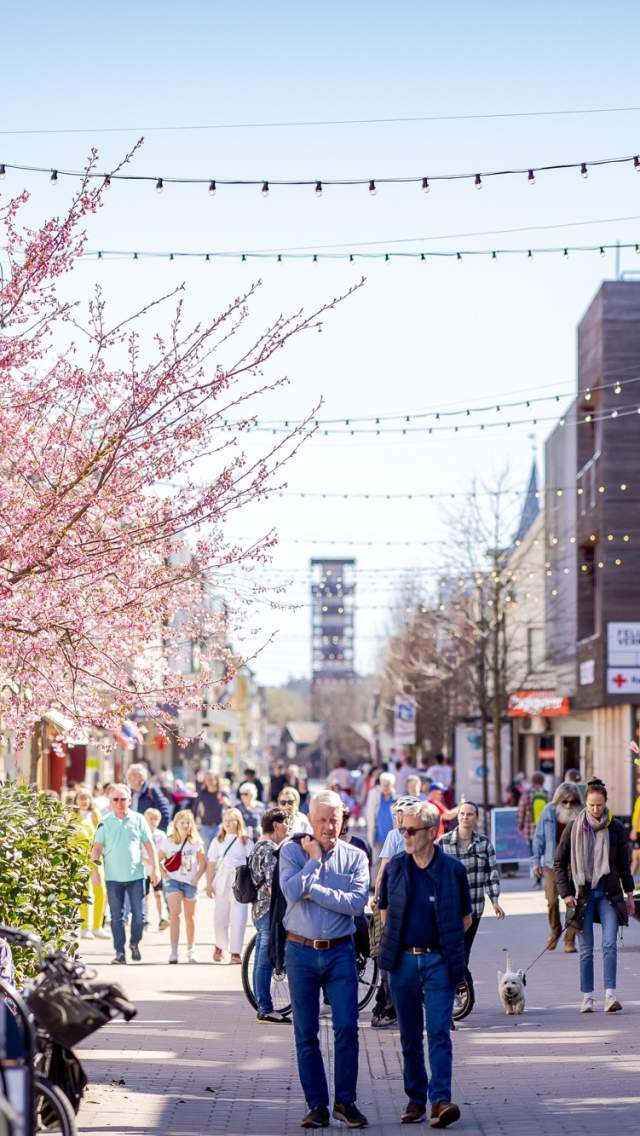 Mennesker som går i gågata og sitter på uteserveringen i Sarpsborg sentrum. Foto.