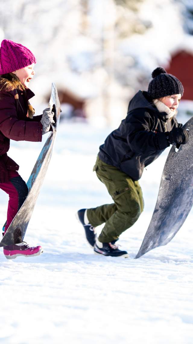 Two girls running with a toboggan to speed down the hill
