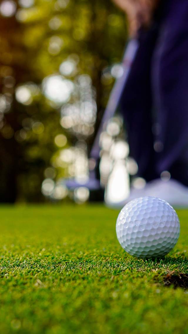 Golfball foran et hull på golfbanen