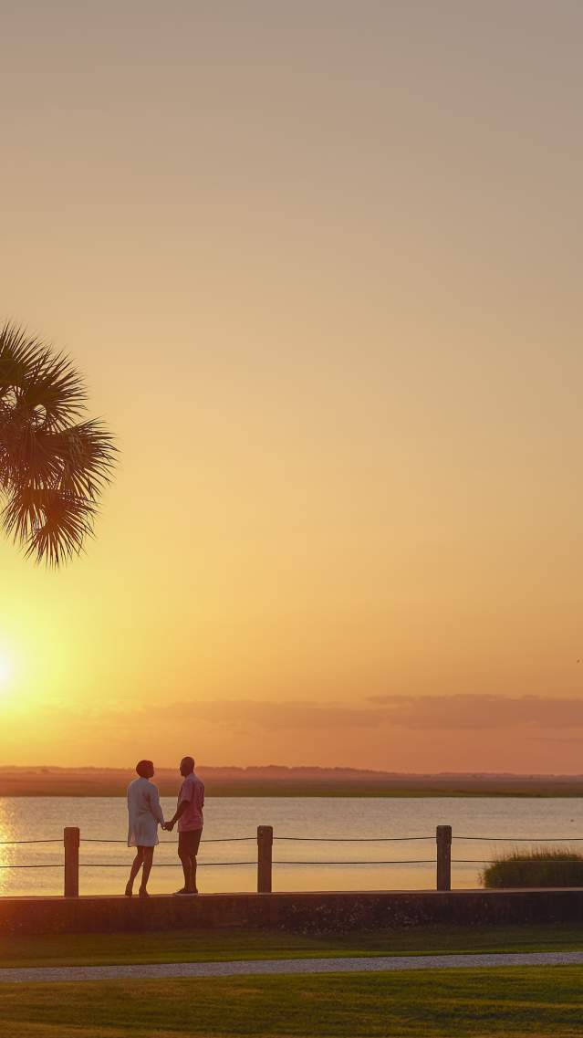 A couple enjoys the sunset along the Jekyll River in the Jekyll Island Historic District