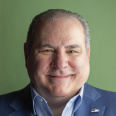 a headshot of Paul Bartolotta with a green background