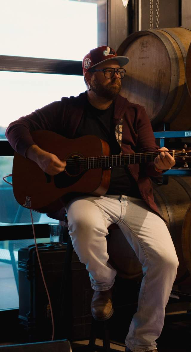 Small band playing in front of a window and wine barrels