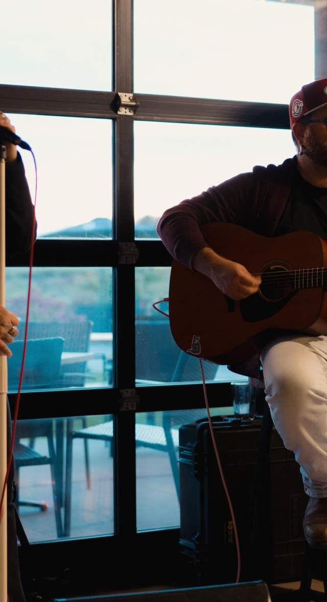Small band playing in front of a window and wine barrels