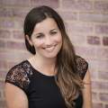 Ashli Workman, director of Tourism, with a black dress, sitting in front of a brick wall.