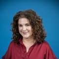 woman with brown hair poses in a burgundy shirt