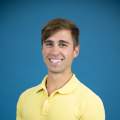 man with blond hair poses in yellow shirt