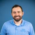 man with brown hair poses in a blue shirt