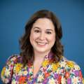 woman with brown hair poses in a colorful flower print dress