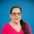 woman with black hair poses in a pink shirt