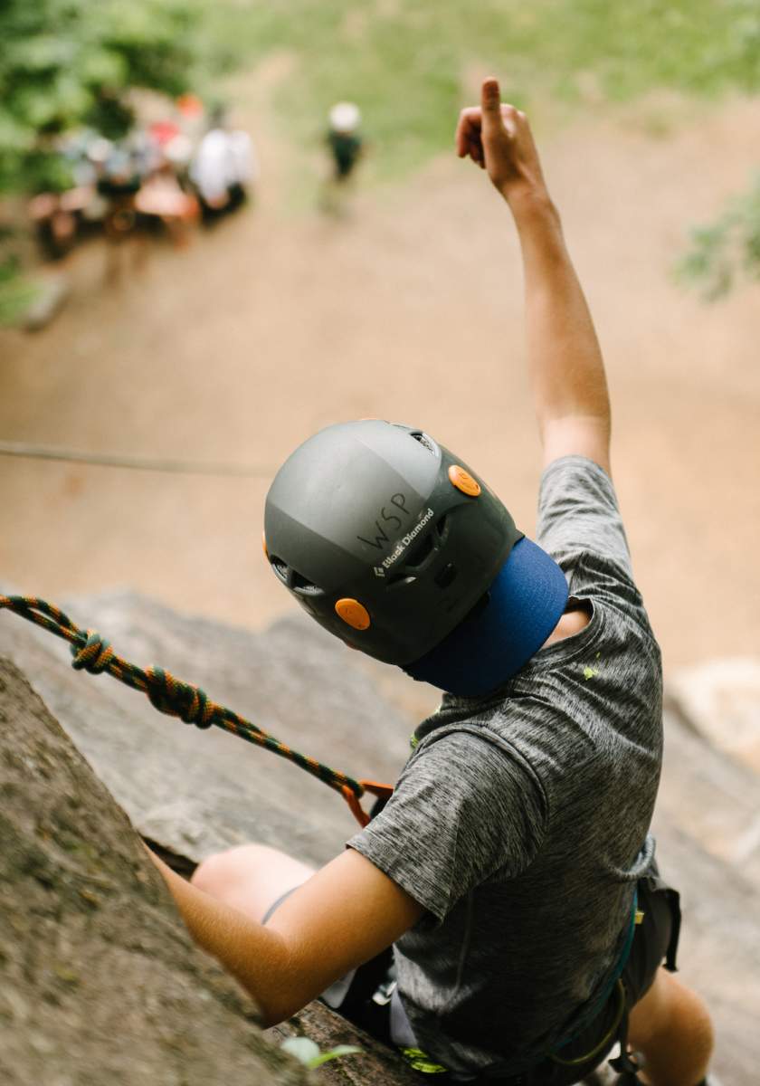 Man rock climbing on a cliff giving a thumbs up
