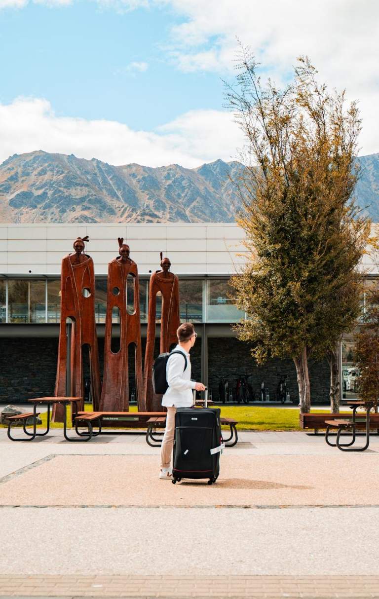 Exterior of airport with traveler walking past with suitcase