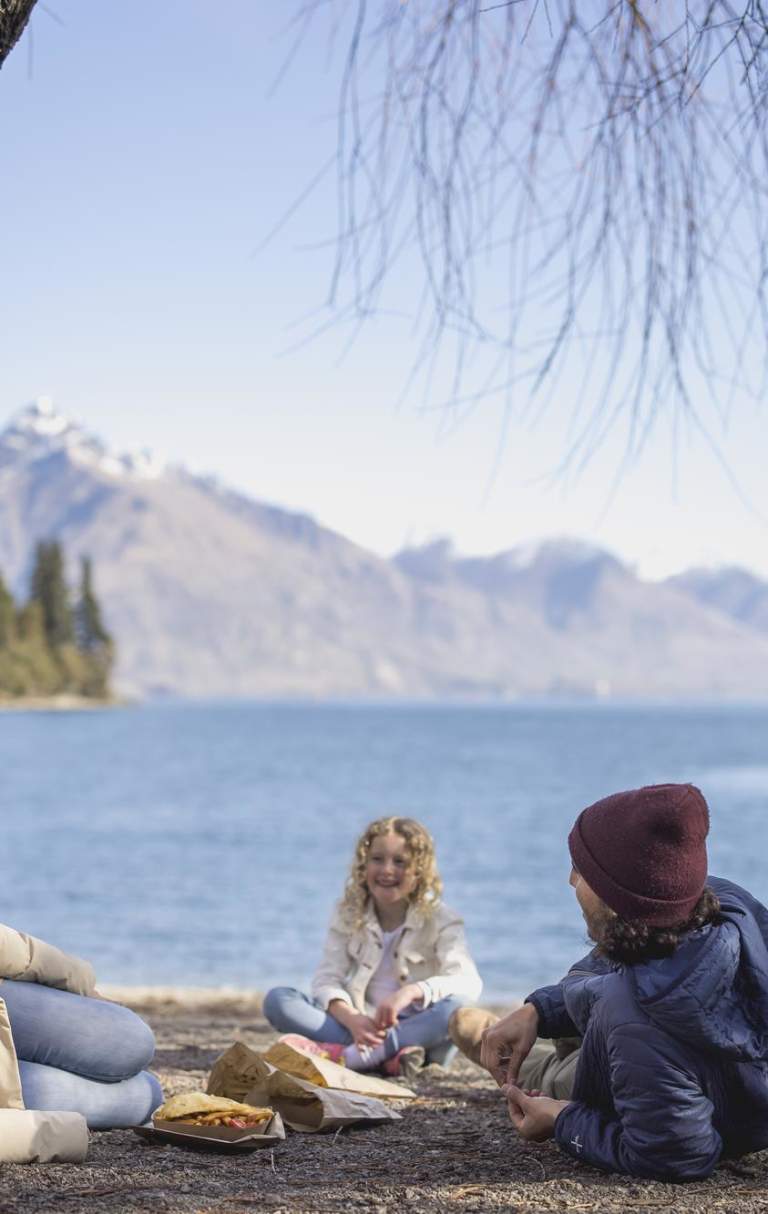 Family eating fish and chips at Queenstown Bay beach