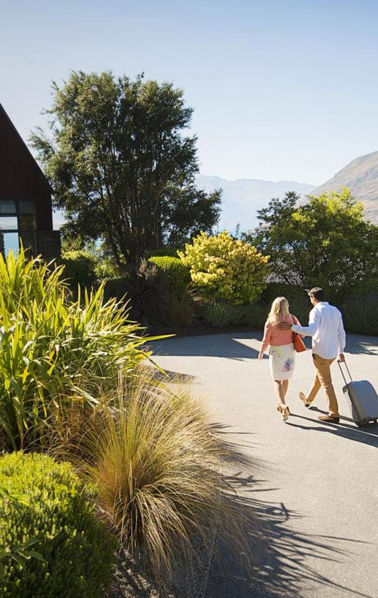 Couple wheeling a suitcase to their Queenstown accommodation