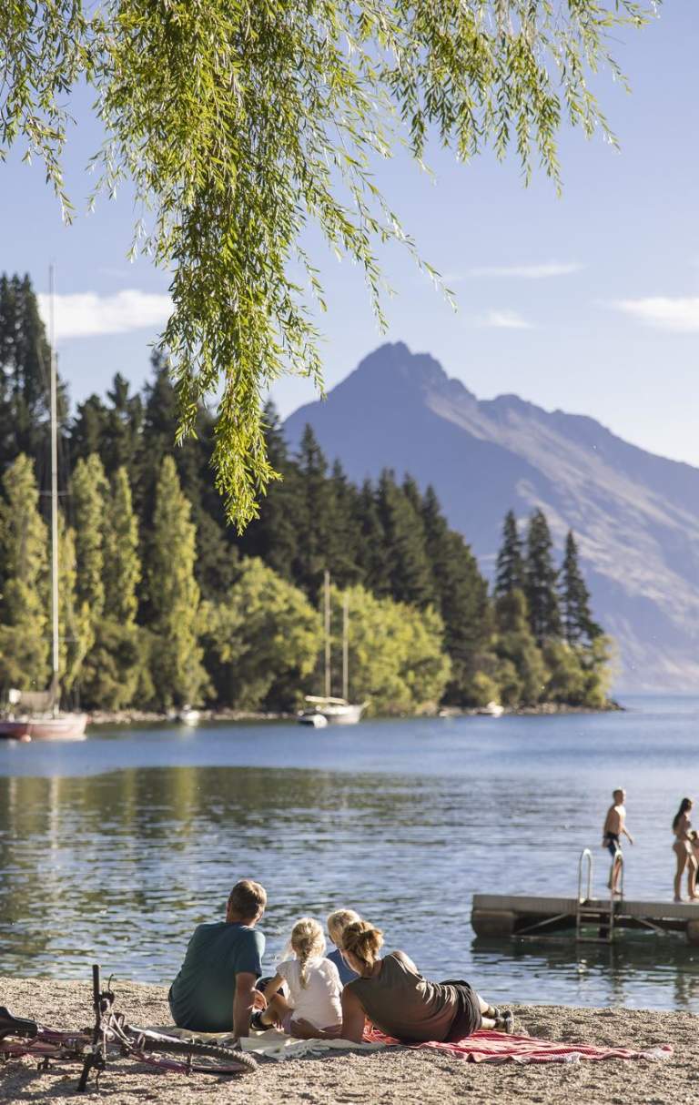 Family sitting by the lake at Queenstown Bay on a summer's day