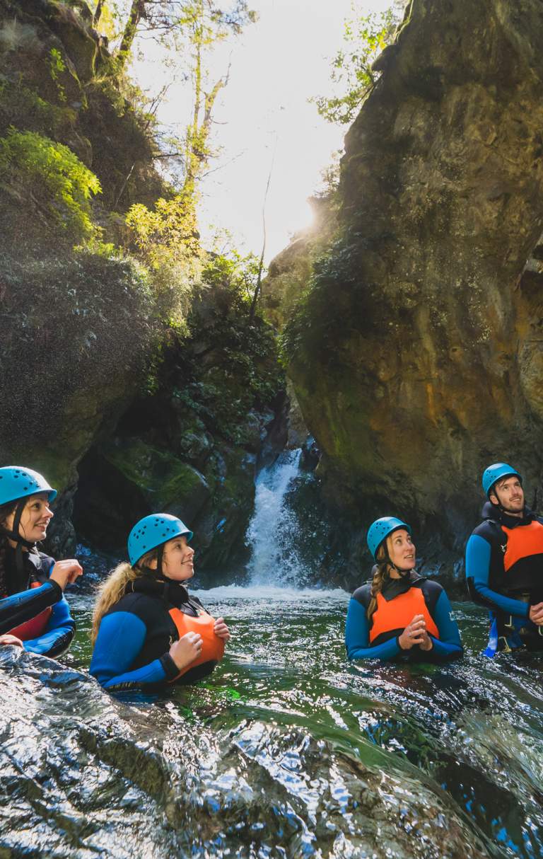 Group of people in wetsuits and helmets in the middle of a canyon