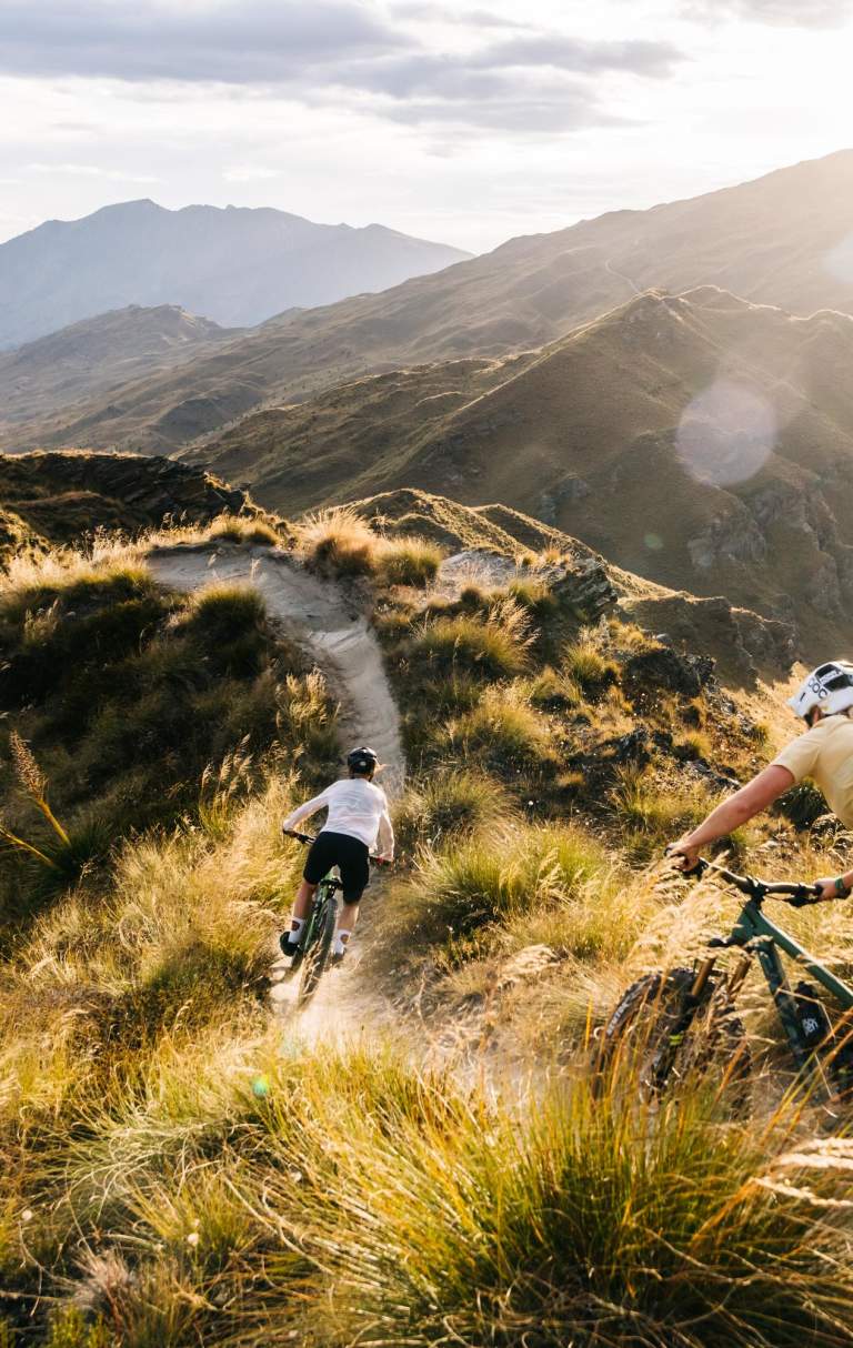 Two people riding mountain bikes through the mountains