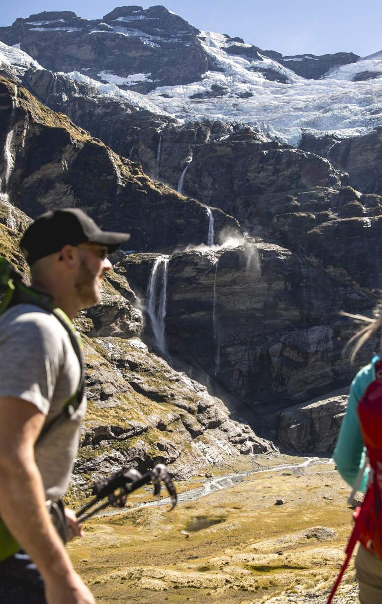 Couple hiking underneath glacier at Earnslaw Burn