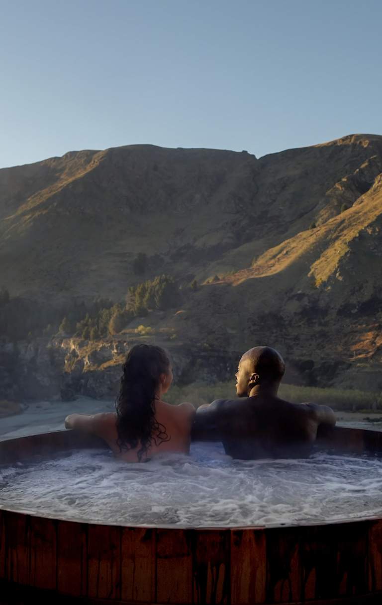 Two people in a hot tub with a beautiful mountain view