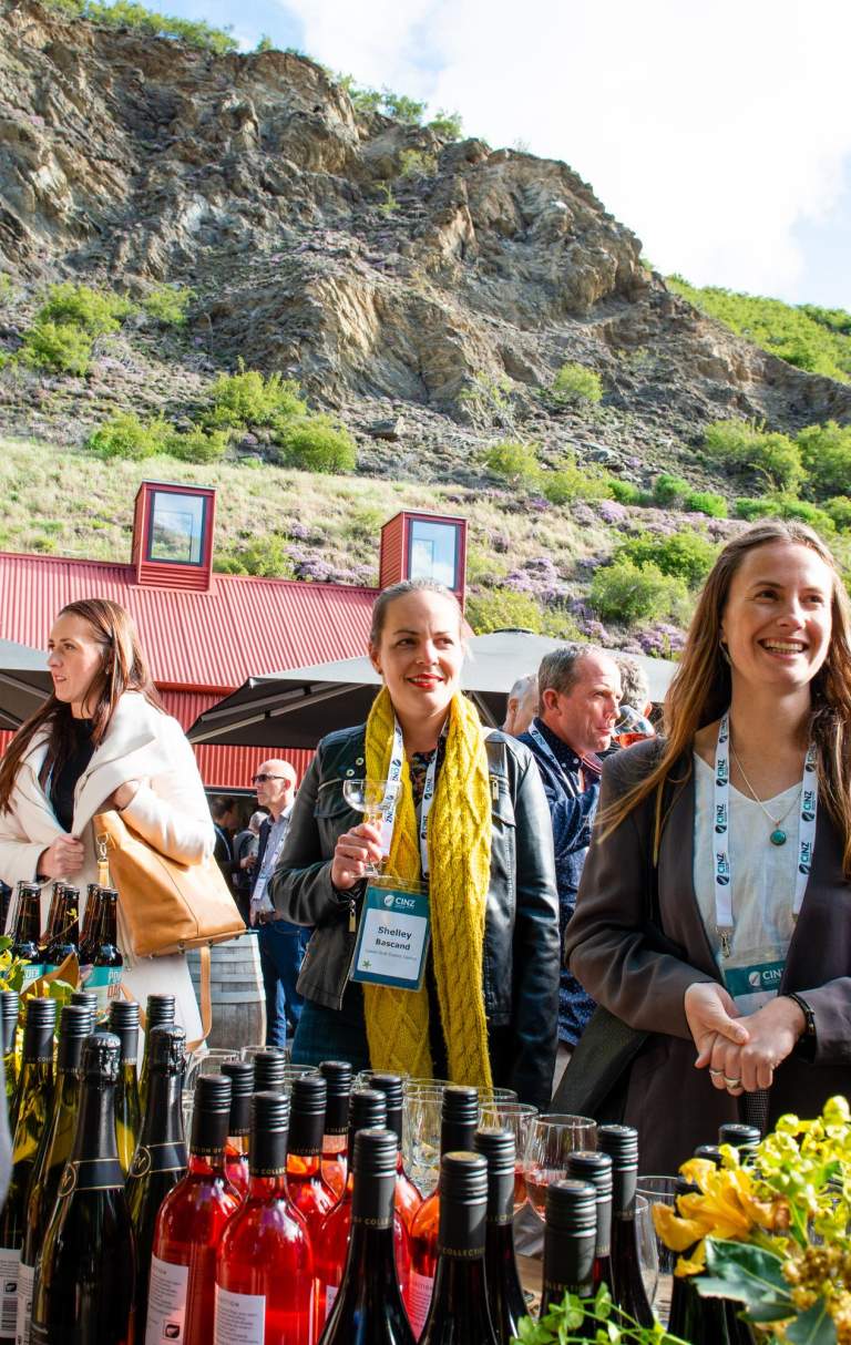 A group of conference attendees standing around a wine tasting table