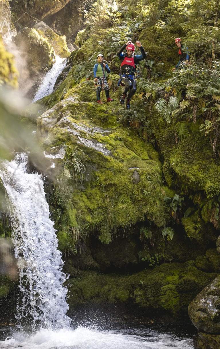 Person canyoning, jumping off a waterfall into a natural spring