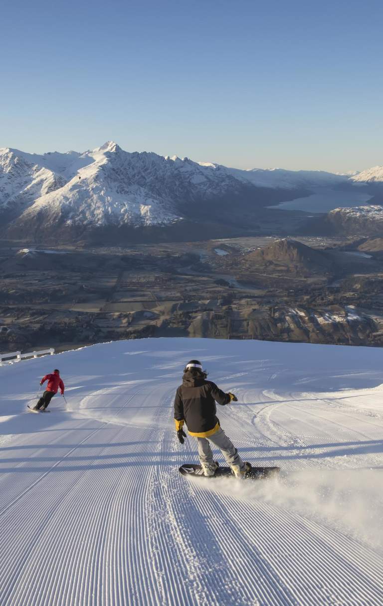 Snowboarders and skiers riding down snowy mountain