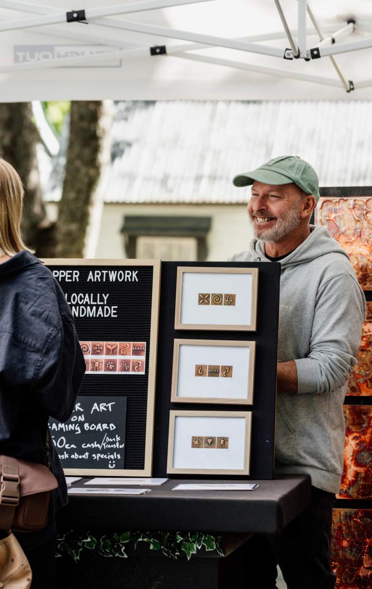Women purchasing local artwork at the Arrowtown Farmers Market