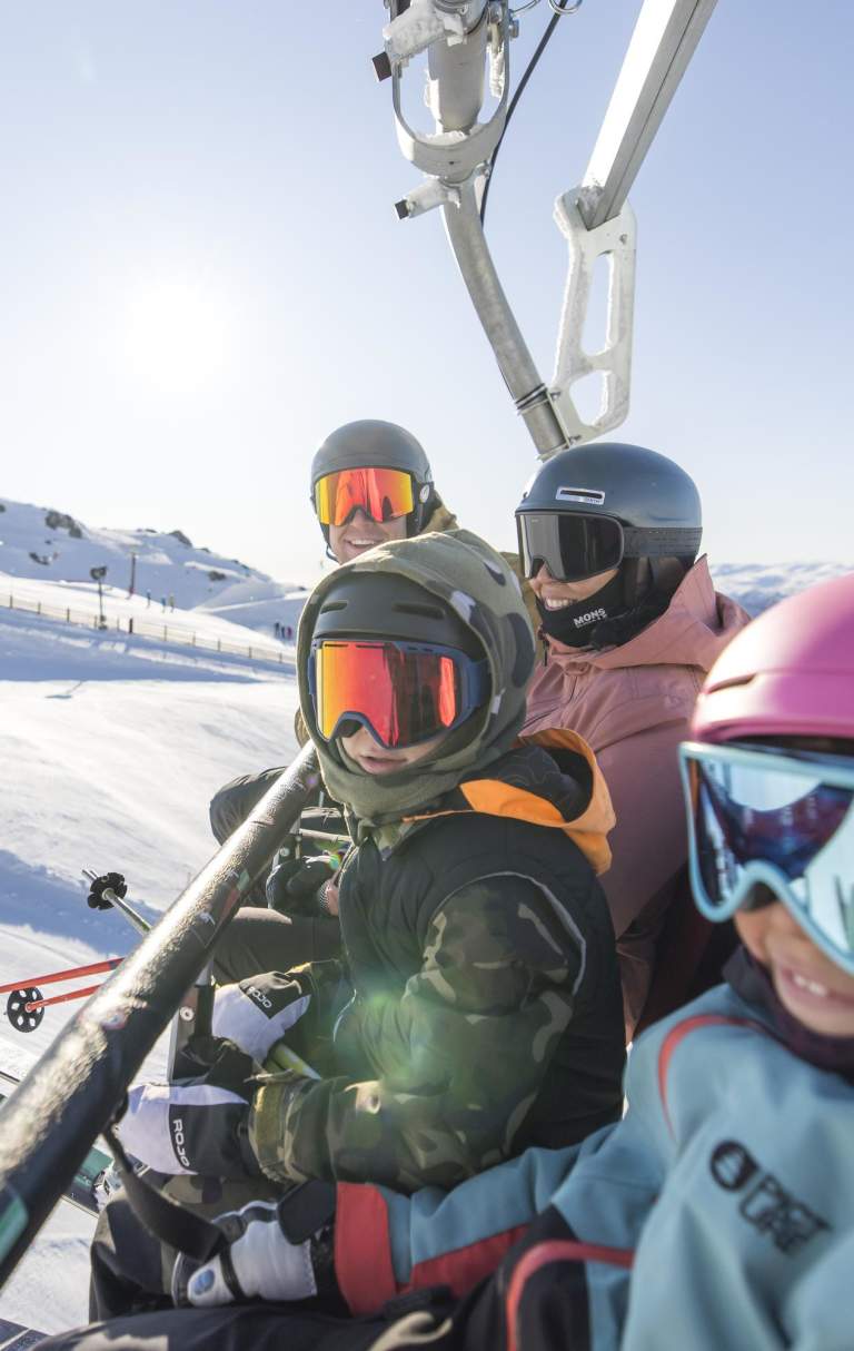 Family in ski gear sitting on a chair lift at Cardrona Ski Resort