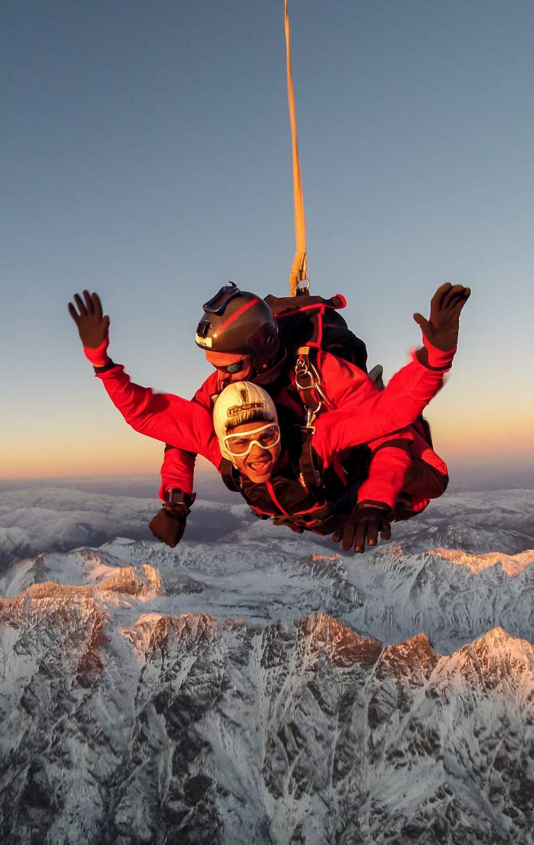 Skydiver high above snowcapped mountains of Queenstown