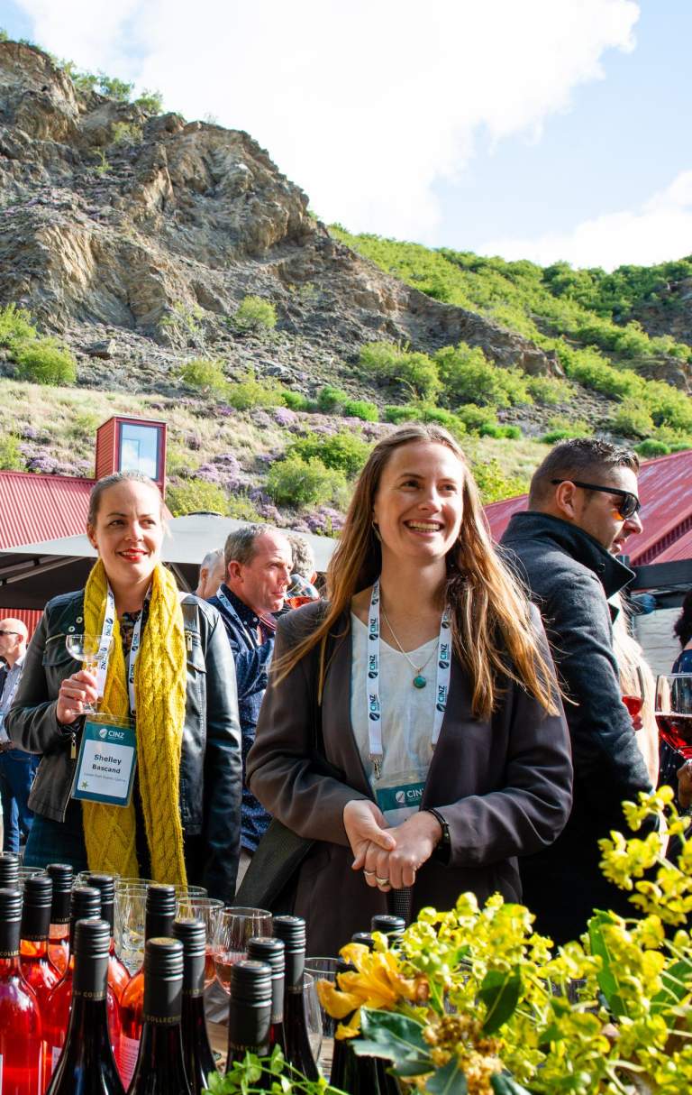 A group of conference attendees standing around a wine tasting table