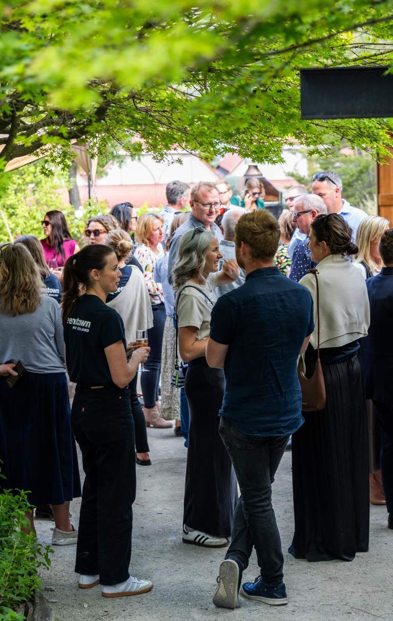 A group of people mingling outside at the Sherwood with trees surrounding the frame