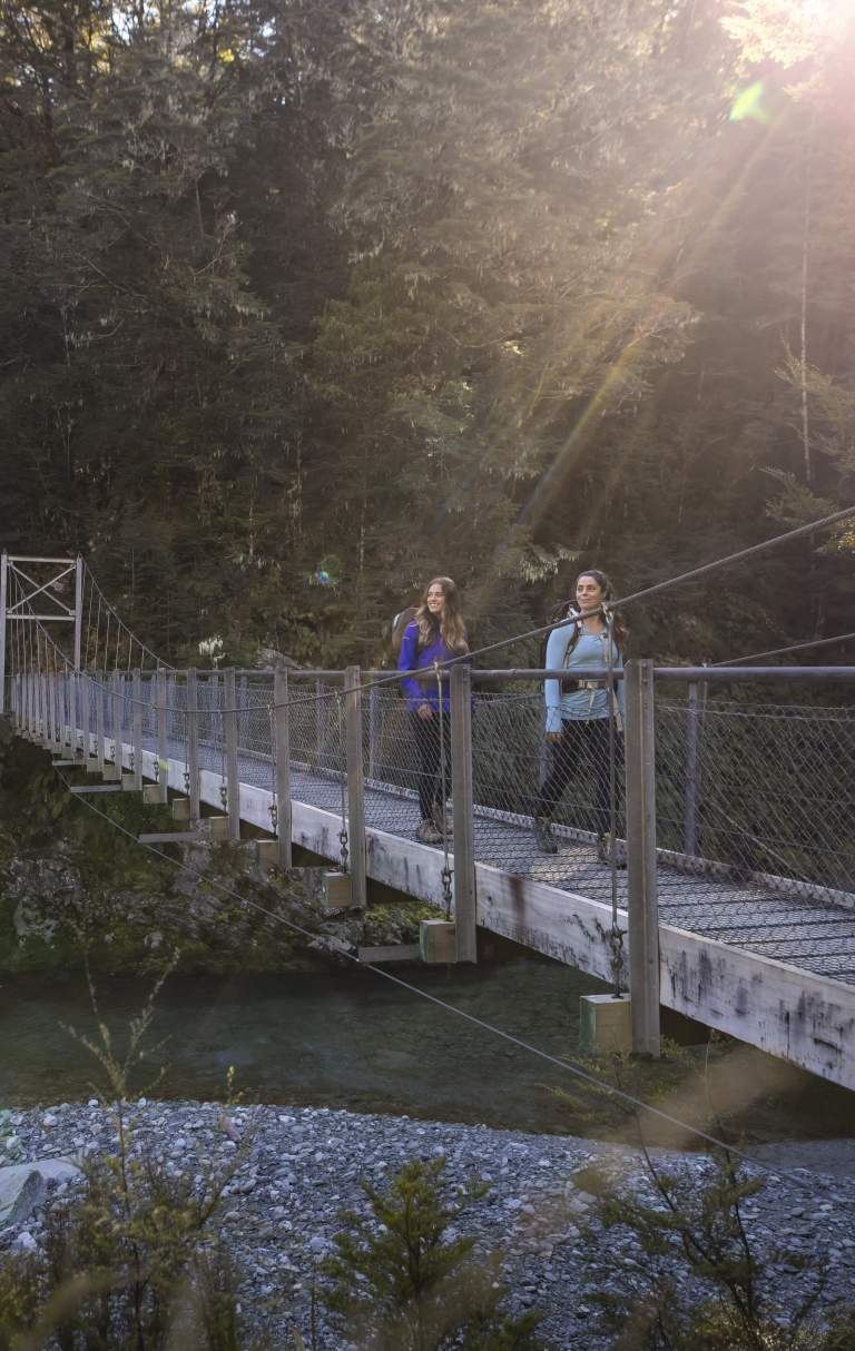 Two female hikers on the Routeburn Track swing bridge