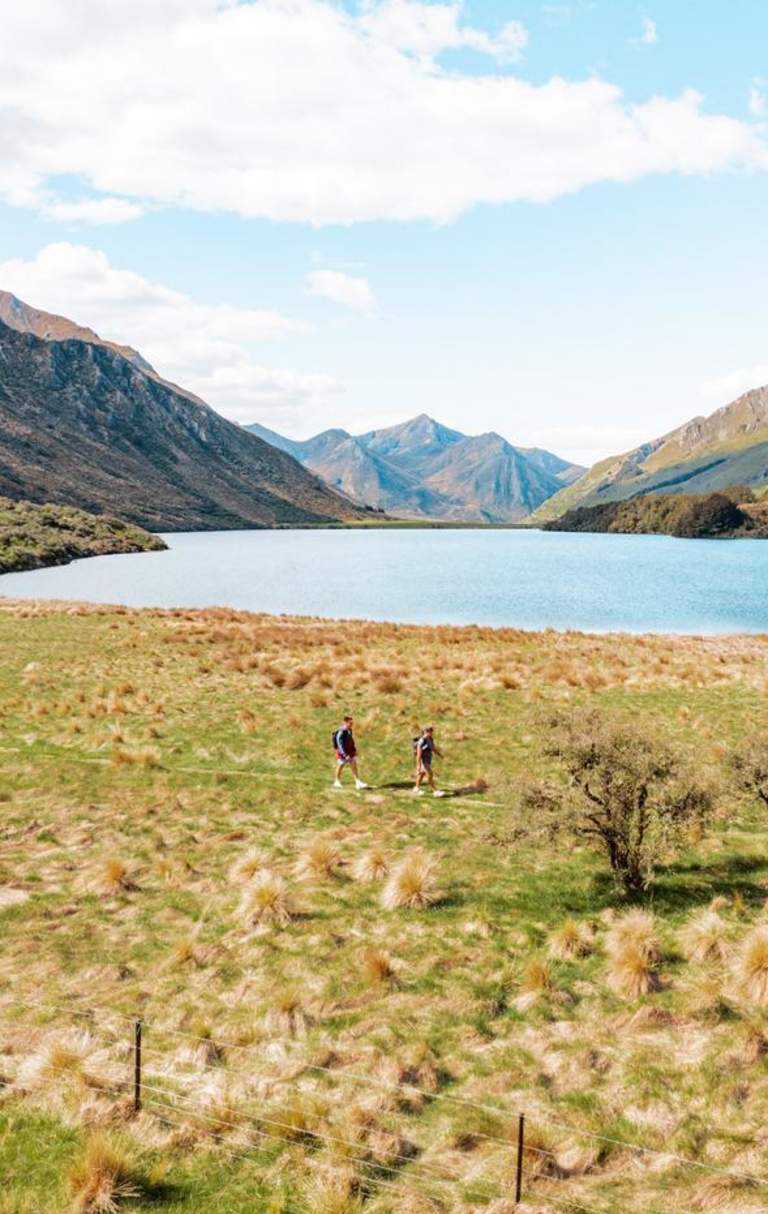Two people walking Moke Lake Loop Track with lake and mountains in view