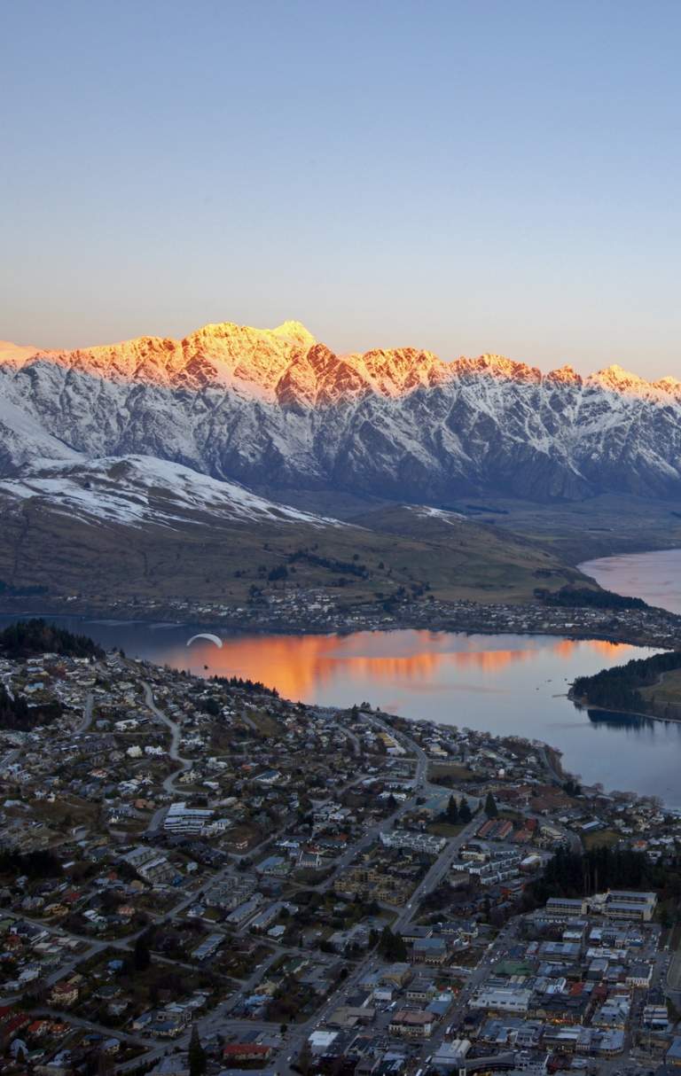 Aerial shot of Queenstown with snow capped mountains, lake and town