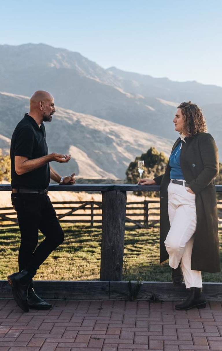 Two people networking outside with a glass of champagne and mountain view in the background